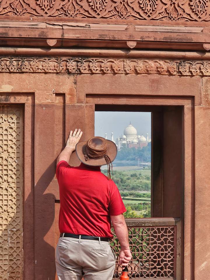 Une personne se penchant à une fenêtre, avec une vue sur le Taj Mahal