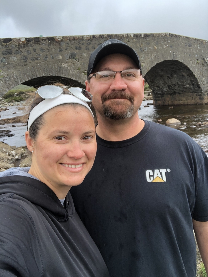 Deux personnes souriantes devant un pont de pierre.