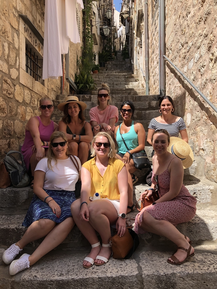 Groupe de femmes assises sur des marches en pierre posant pour une photo.