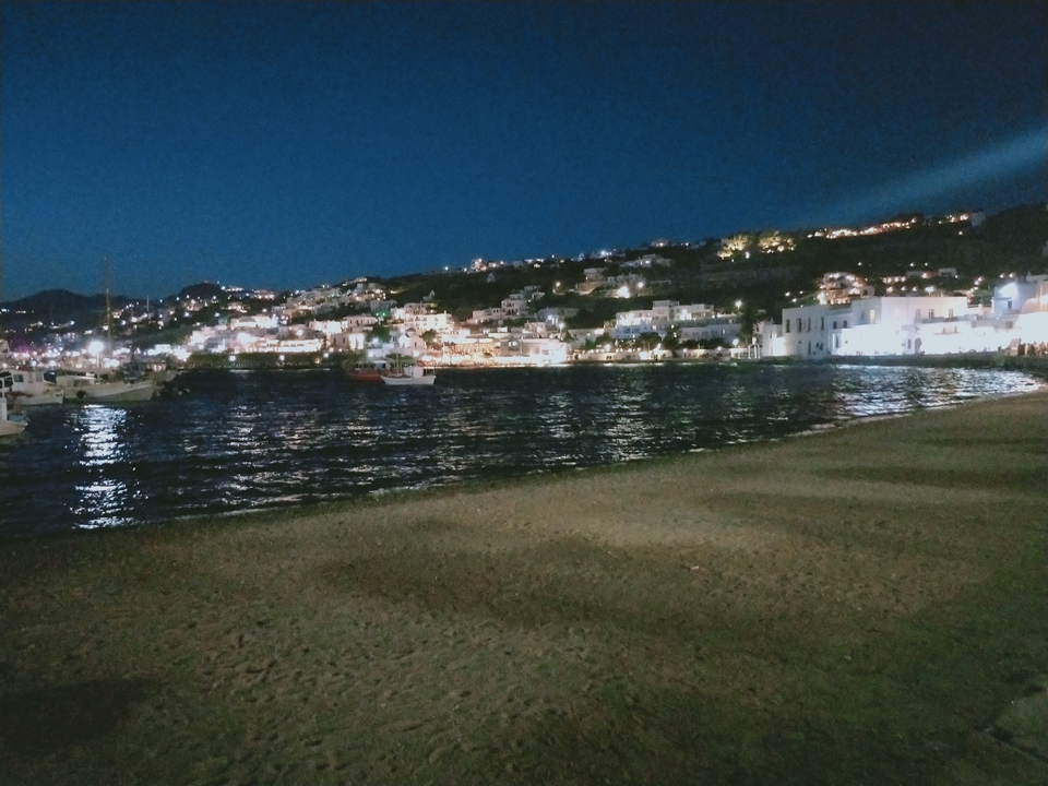 Night view of a village by the water with lit buildings.