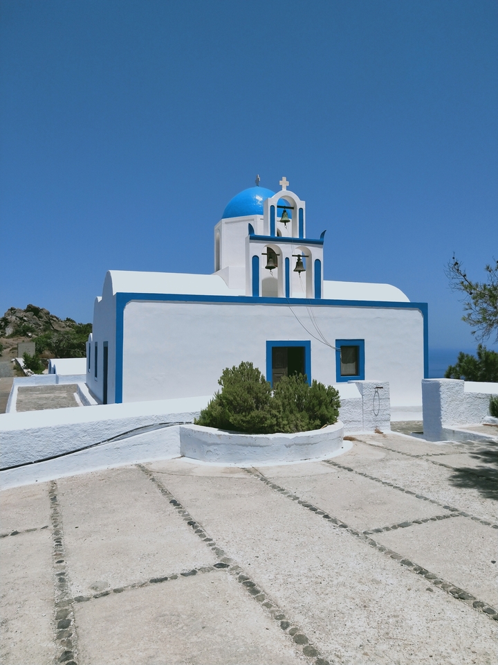 White and blue-domed church with clear blue sky.
