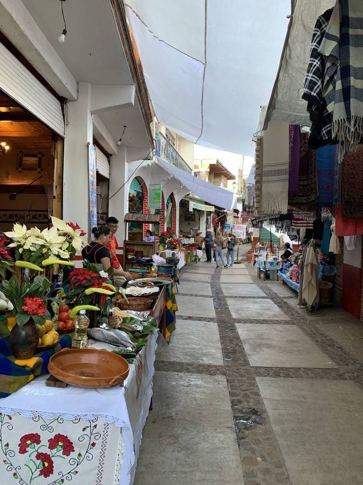 Étal de marché rustique avec divers produits et foule animée.