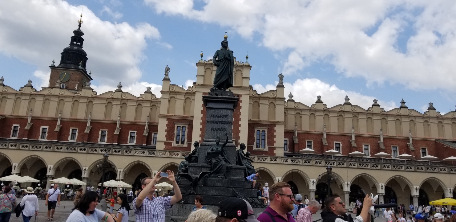 Une place animée avec une statue proéminente et des bâtiments historiques en arrière-plan.