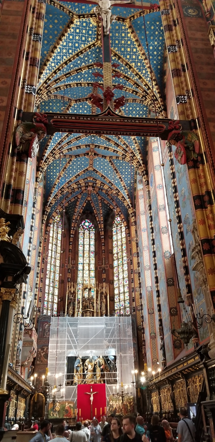 Intérieur complexe d'une église gothique avec des vitraux et un plafond orné.