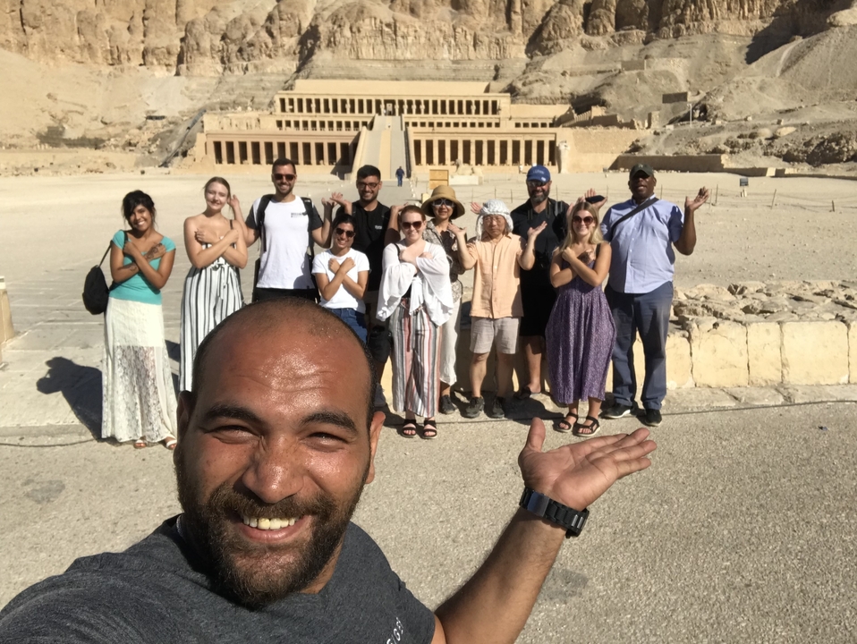 Photo de groupe devant une structure de temple ancien dans un décor désertique.