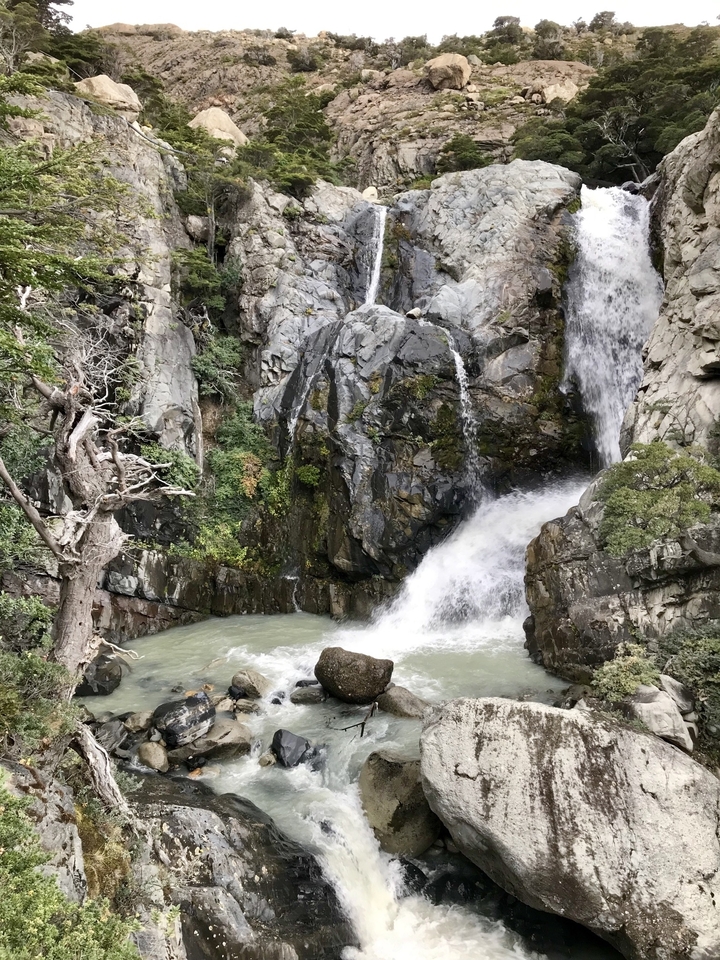 Cascade entourée de falaises rocheuses et de végétation.