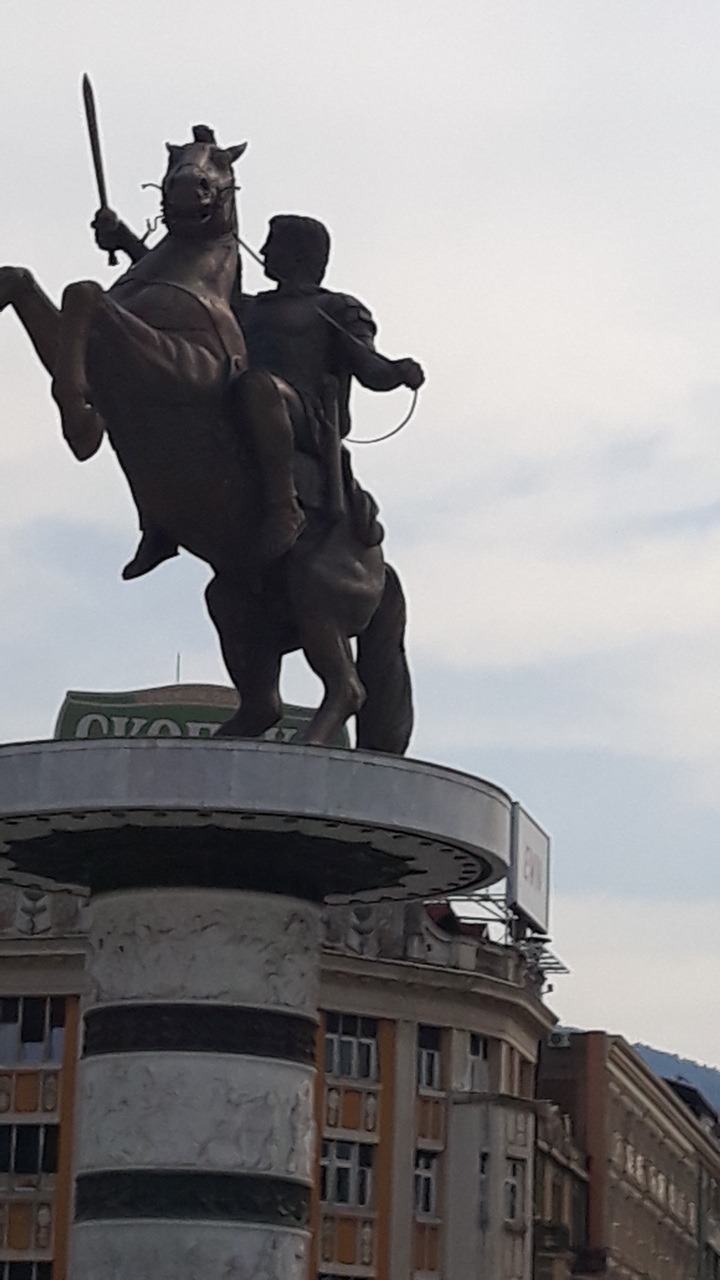 Statue au sommet d'un bâtiment avec un panneau de logo en dessous.