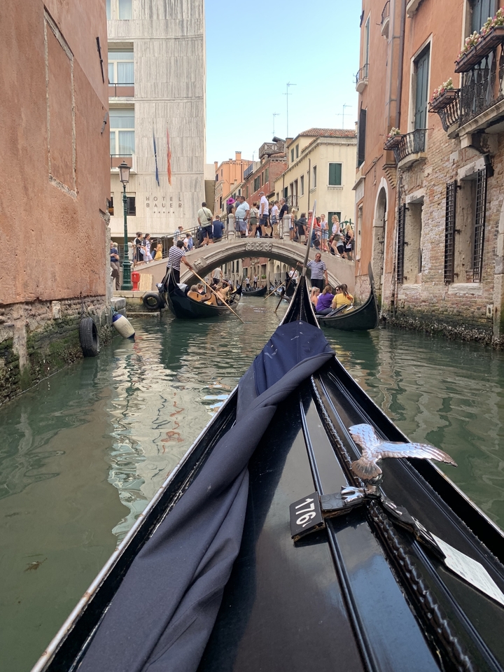 Vue depuis une gondole à Venise avec des personnes et un pont.