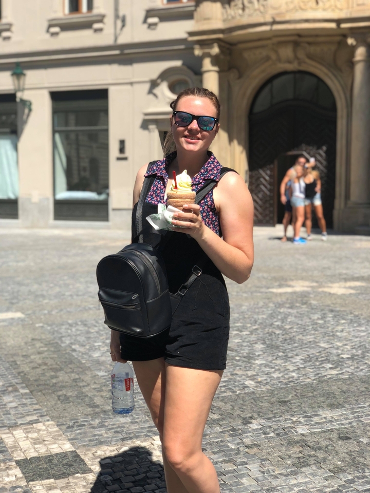 Femme tenant un dessert debout sur une place.