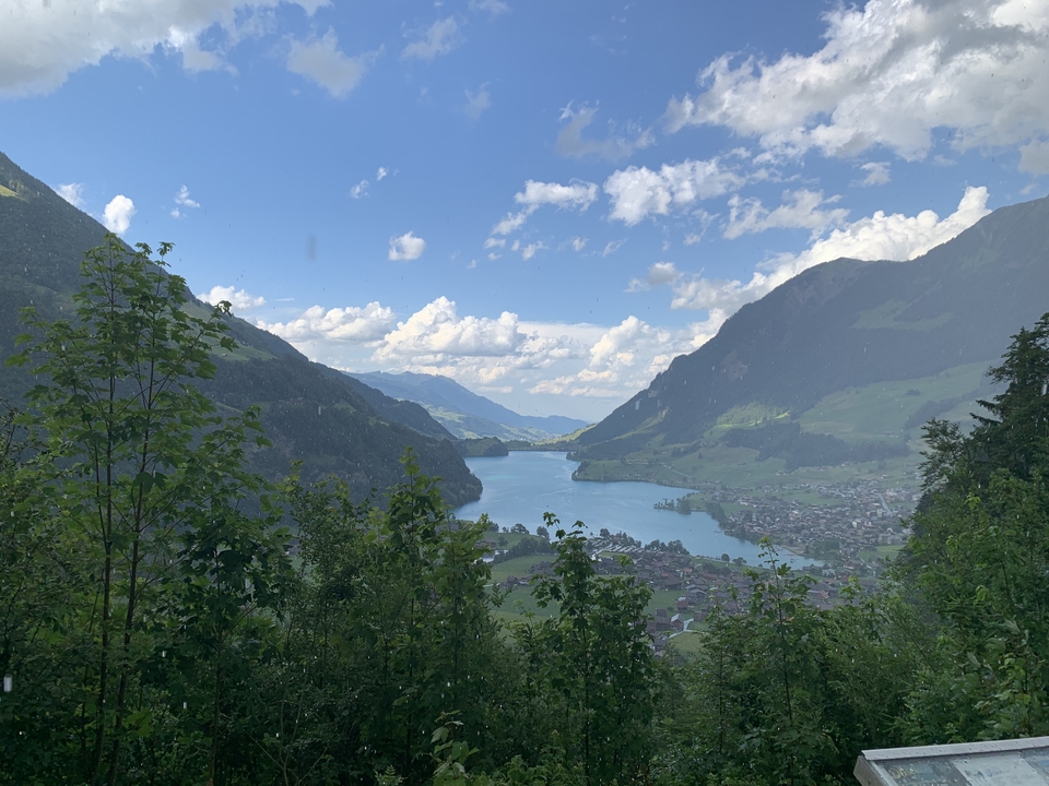 Vue d'un lac entouré de montagnes sous un ciel nuageux.