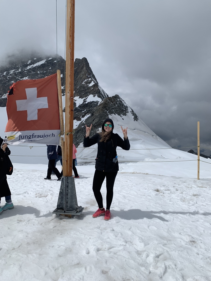Personne au sommet d'une montagne enneigée à côté d'un drapeau.