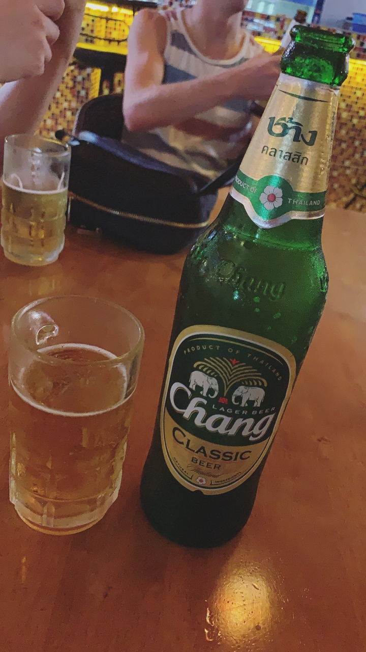 Bouteille de bière Chang avec un verre sur une table.