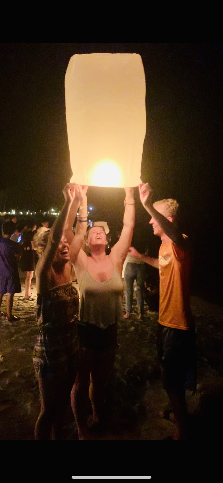 Group of people releasing a sky lantern at night.