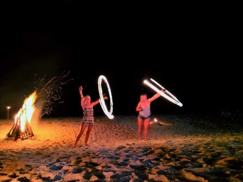 Danse du feu sur une plage la nuit.