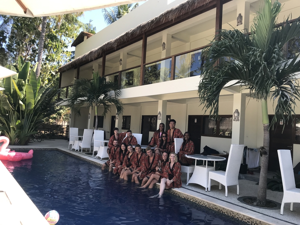 Group of people in robes sitting by a pool.