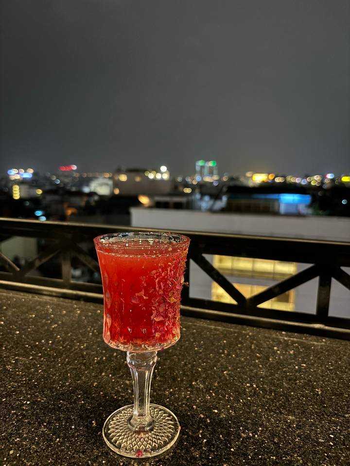 Verre à cocktail rouge avec les lumières de la ville en arrière-plan.