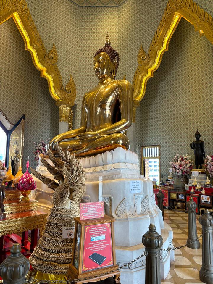 Statue dorée de Bouddha couché dans un temple décoré.