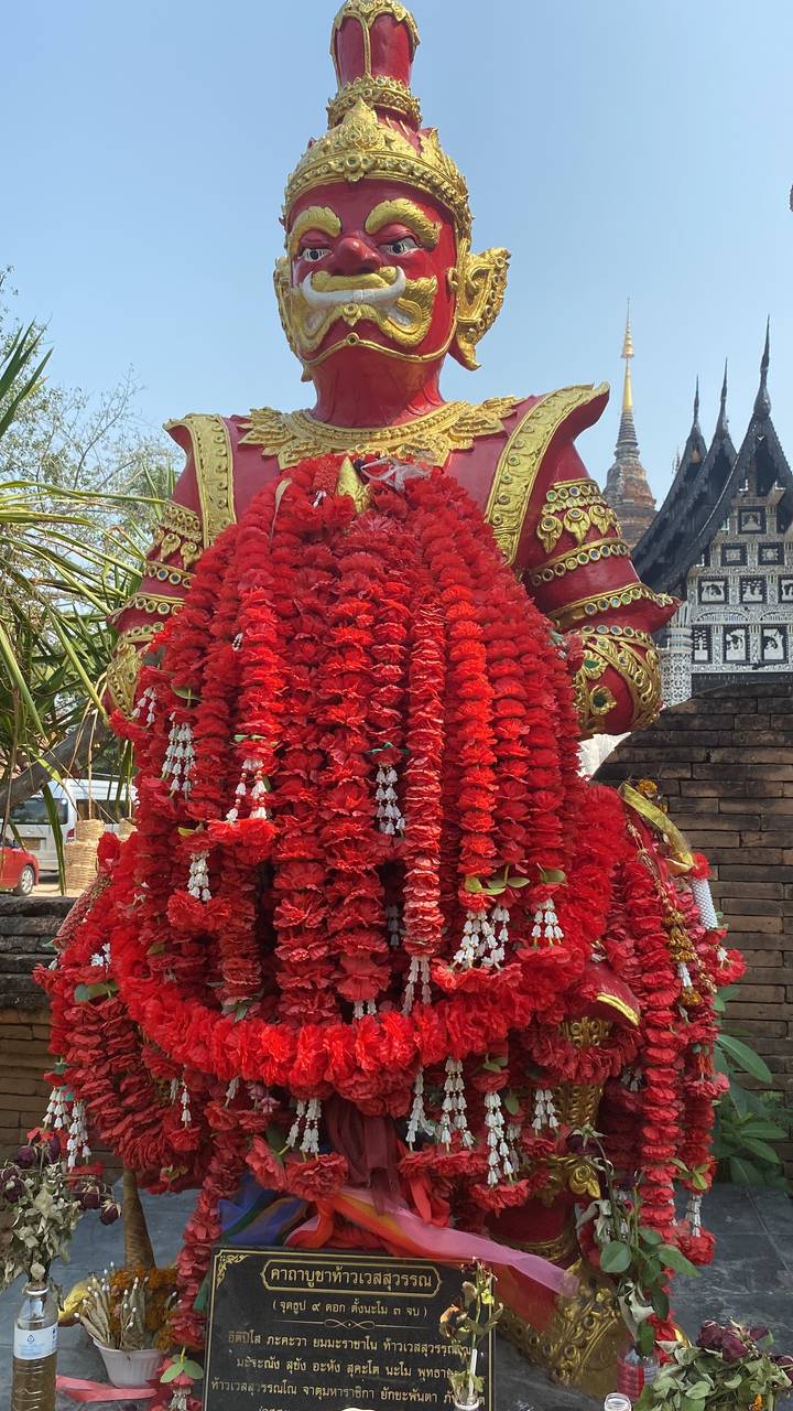 Une statue décorée avec des guirlandes rouges.
