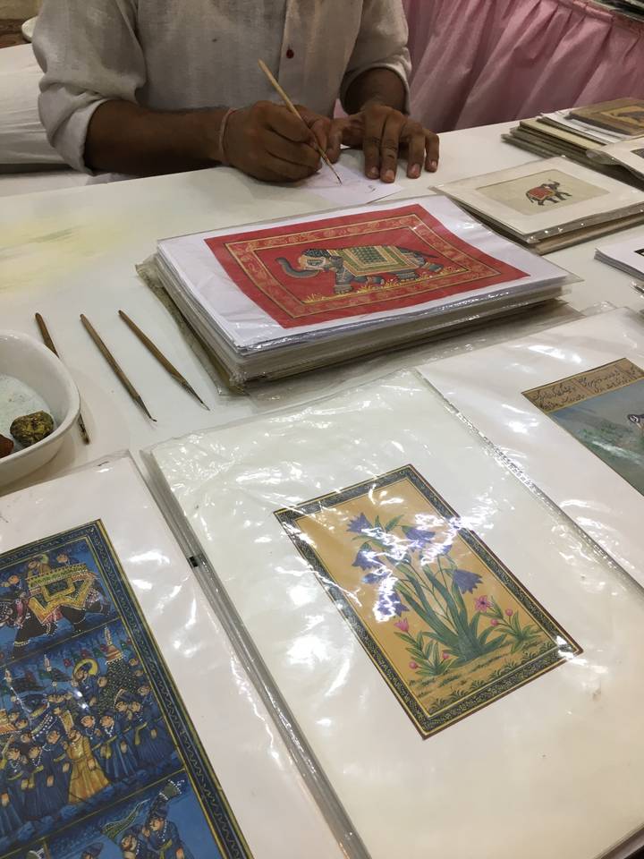 Personne travaillant sur de l'art traditionnel avec de la peinture et des pinceaux.