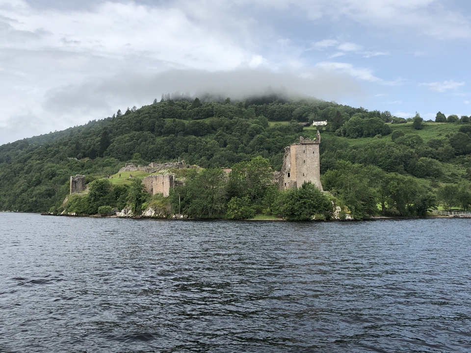Ruines d'un château historique au bord d'un lac avec un ciel nuageux