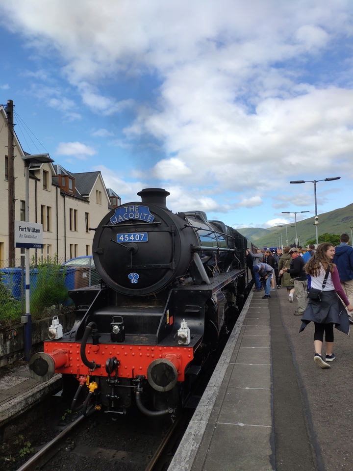 Train à vapeur nommé 'The Jacobite' en gare avec des passagers qui montent à bord.