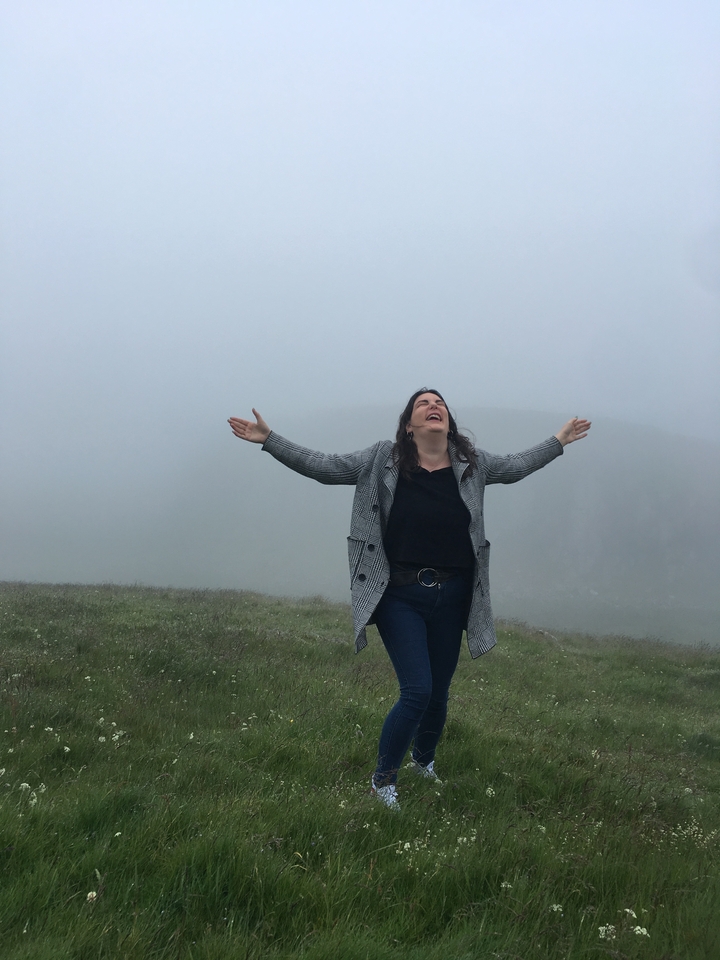 Femme debout les bras étendus par un jour de brouillard.