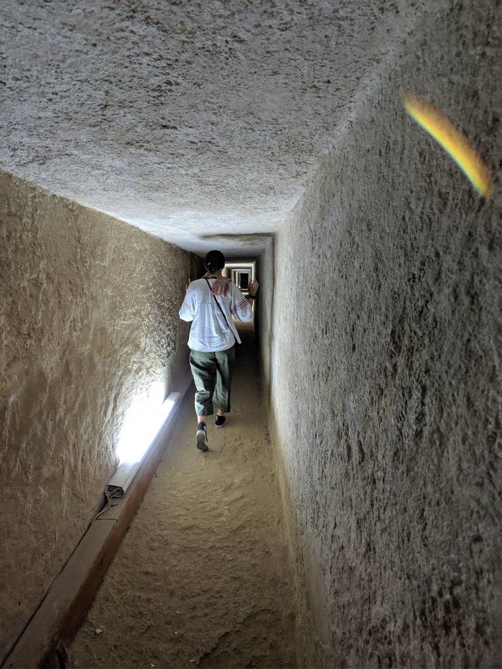 Person walking through a narrow ancient corridor.