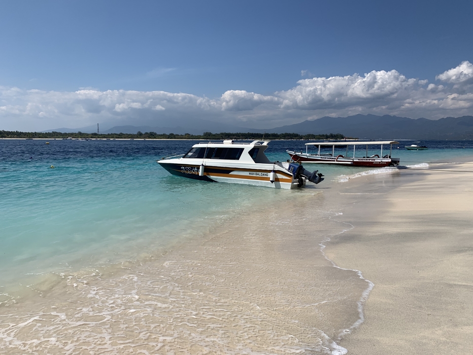 Boats lined up along the shore of a clear beach.