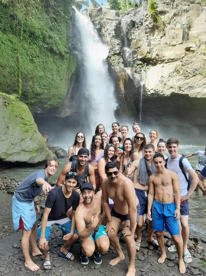 Group of people posing in front of a waterfall.