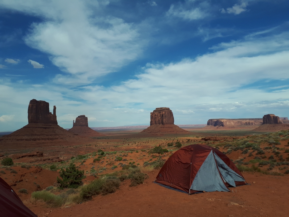 Paysage de Monument Valley avec des formations rocheuses emblématiques et des tentes.