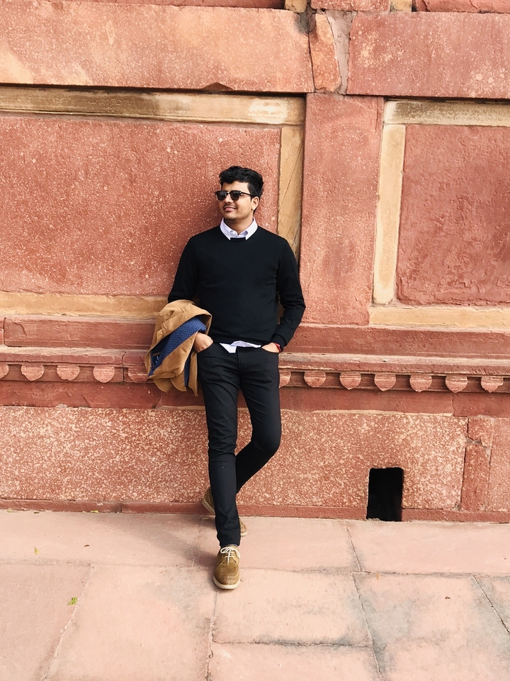 Homme posant contre un mur de grès rouge.