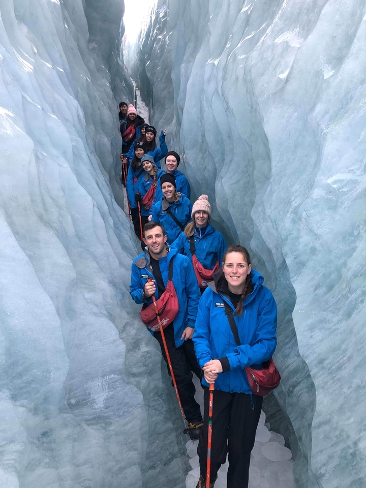 Groupe de personnes en vestes bleues à l'intérieur d'une crevasse glacée.