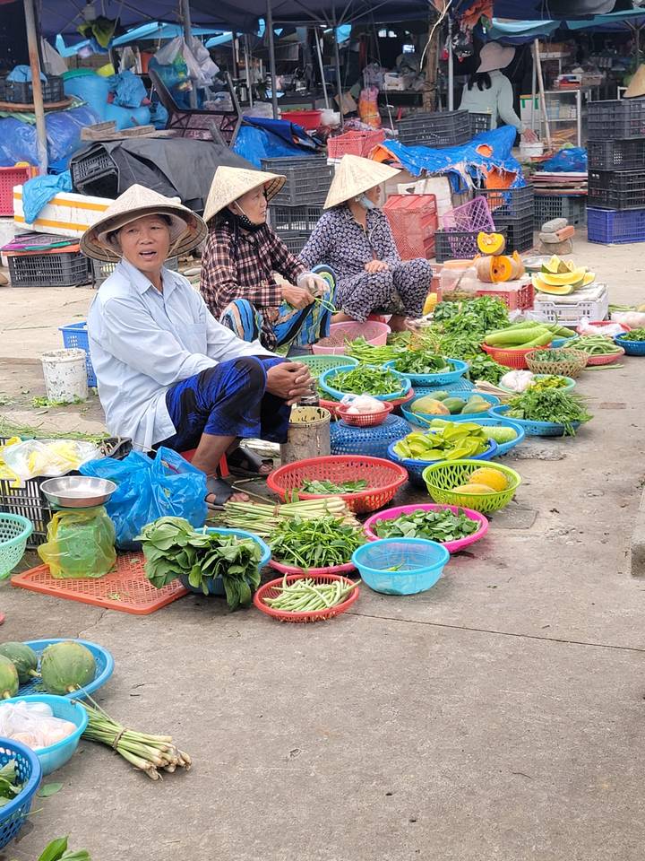 Scène de marché avec des vendeurs qui vendent des légumes.