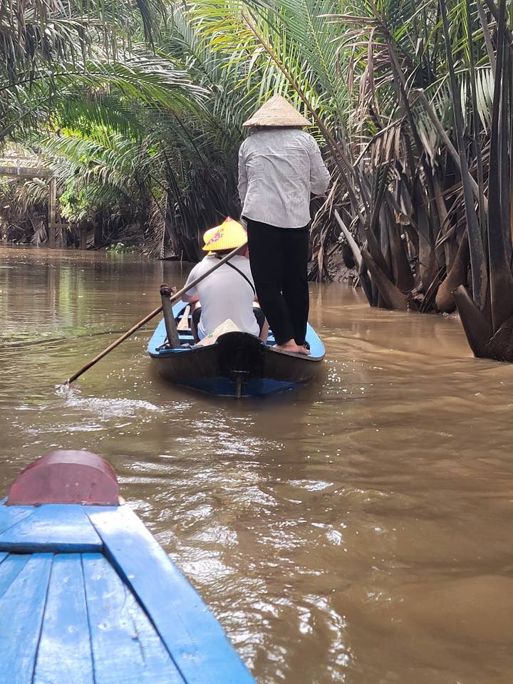 Petit bateau sur une voie navigable étroite bordée d'arbres.