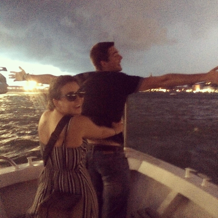 Deux personnes posant sur un bateau pendant le coucher de soleil.