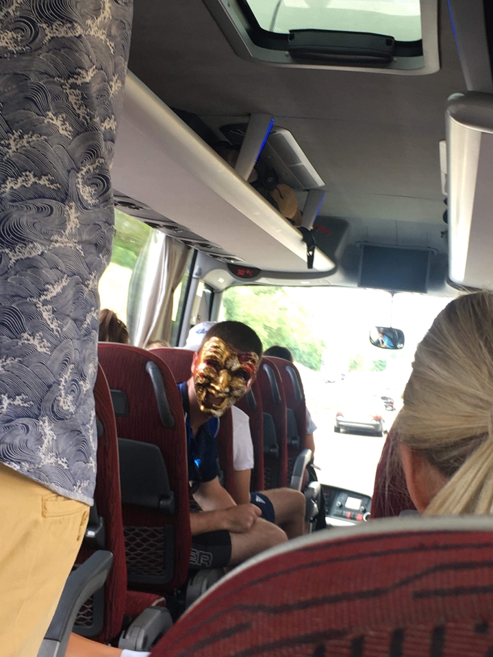 Personne portant un masque théâtral dans un bus.