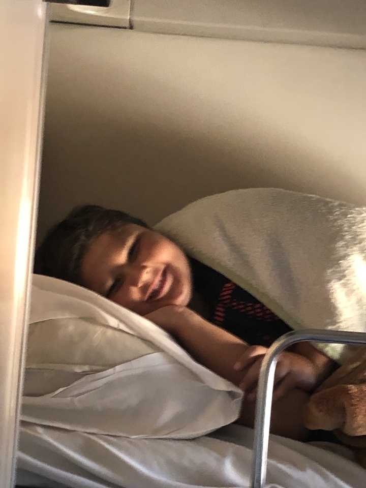 Personne allongée sous une couverture, probablement dans un avion.