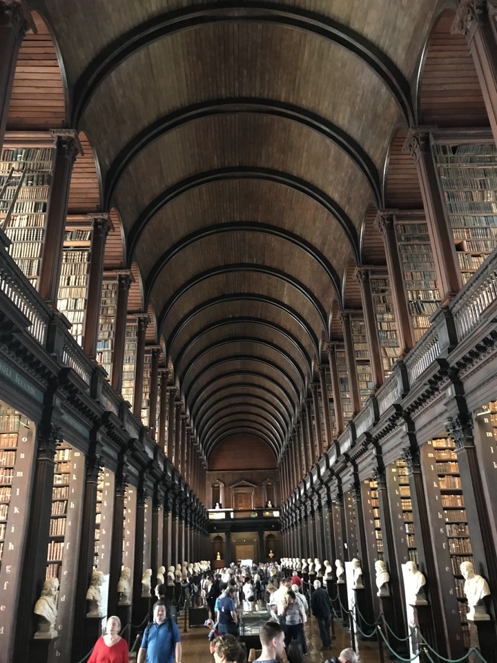 Interior of a historic library with arched wooden ceiling and long bookshelves.