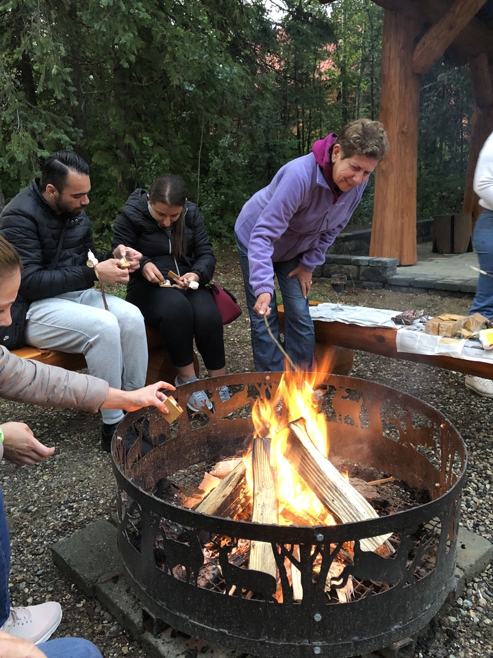 Groupe de personnes autour d'un feu de camp, faisant griller des guimauves.