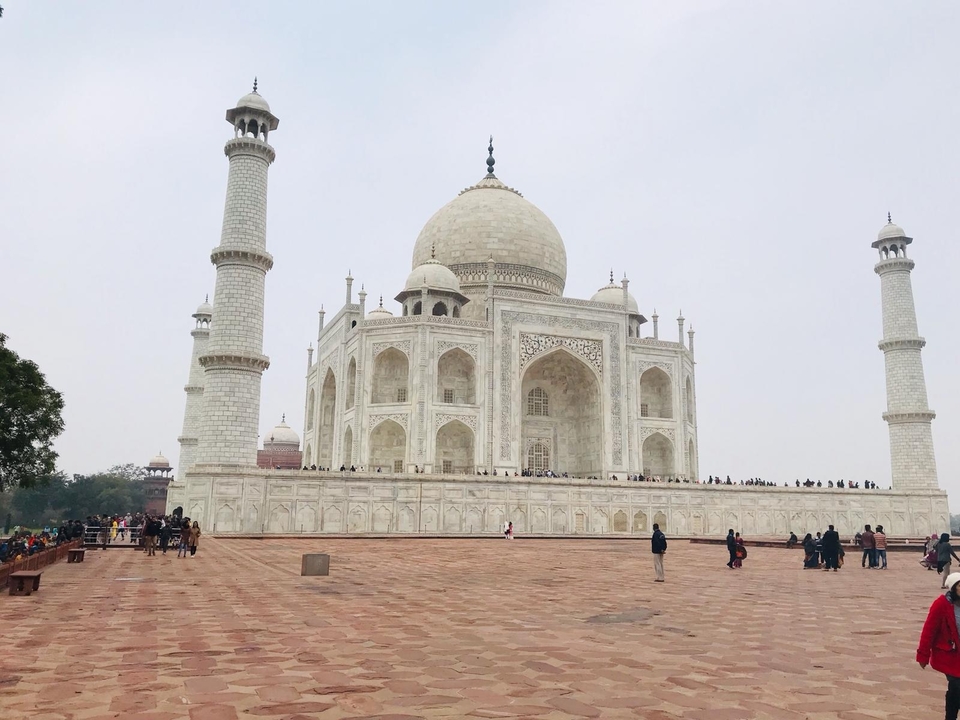 Taj Mahal sous un ciel nuageux avec des visiteurs.