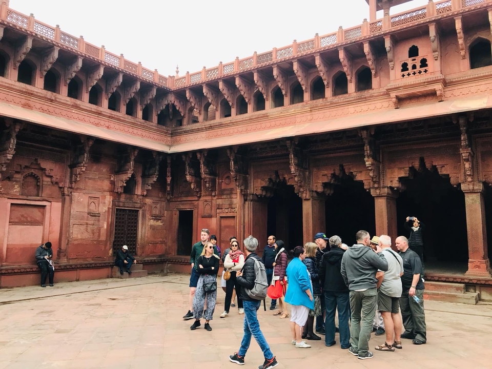Groupe de touristes dans une cour historique en grès rouge.