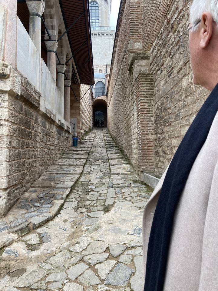 Étroit sentier pavé entre des murs de briques historiques.