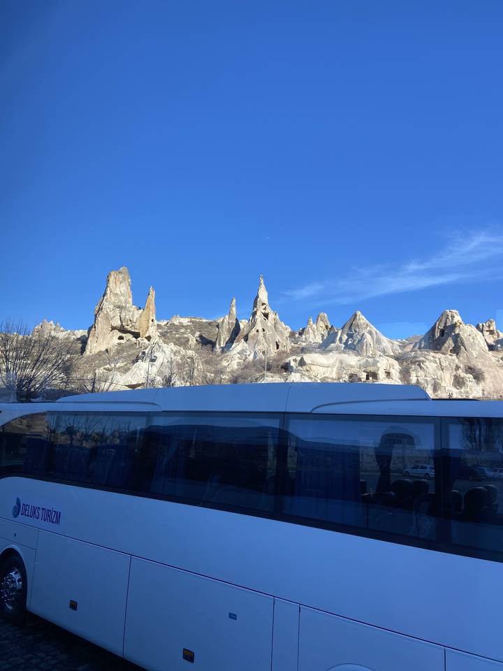 Formations rocheuses uniques avec un ciel bleu dégagé et un bus au premier plan.