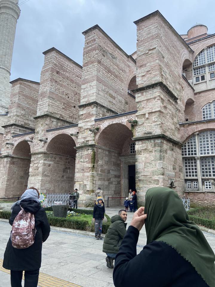 Bâtiment historique en pierre avec des personnes à proximité.