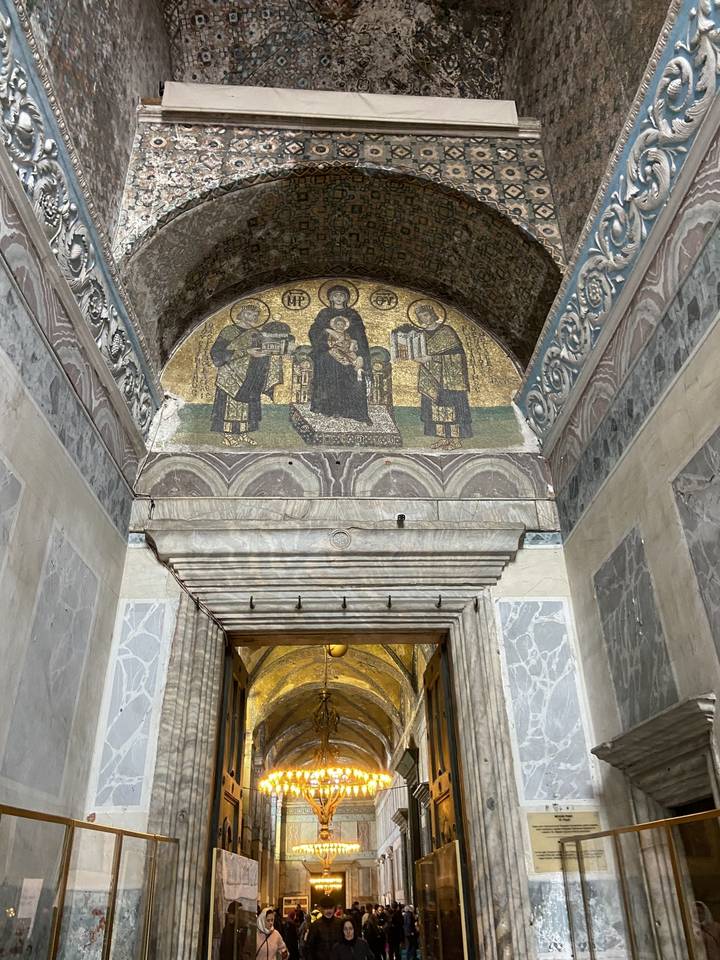Mosaïque religieuse ornée au-dessus d'une porte dans un bâtiment historique.