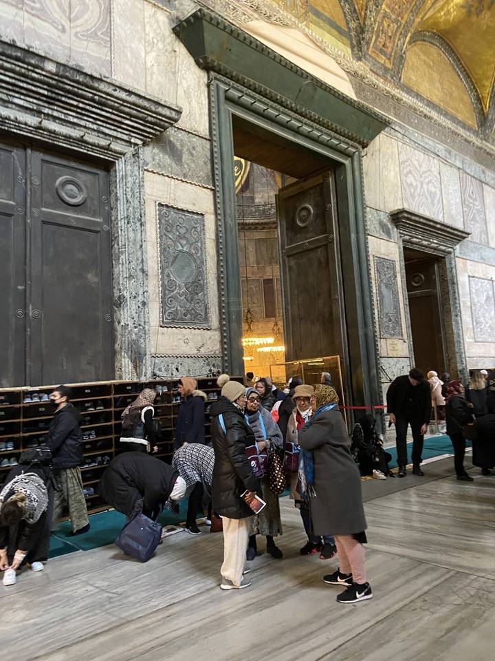 Des personnes entrent dans un bâtiment historique avec de grandes portes.