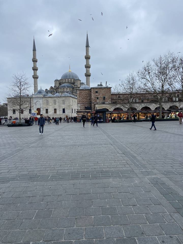 Place publique avec une mosquée et des gens qui marchent.
