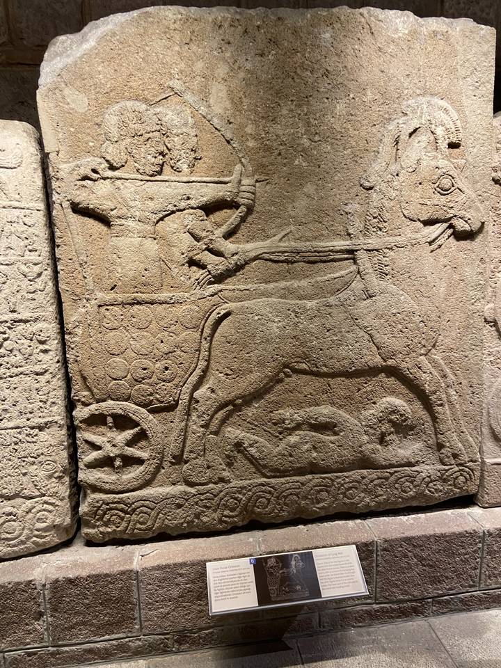 Relief en pierre antique sculpté représentant un char et des soldats.