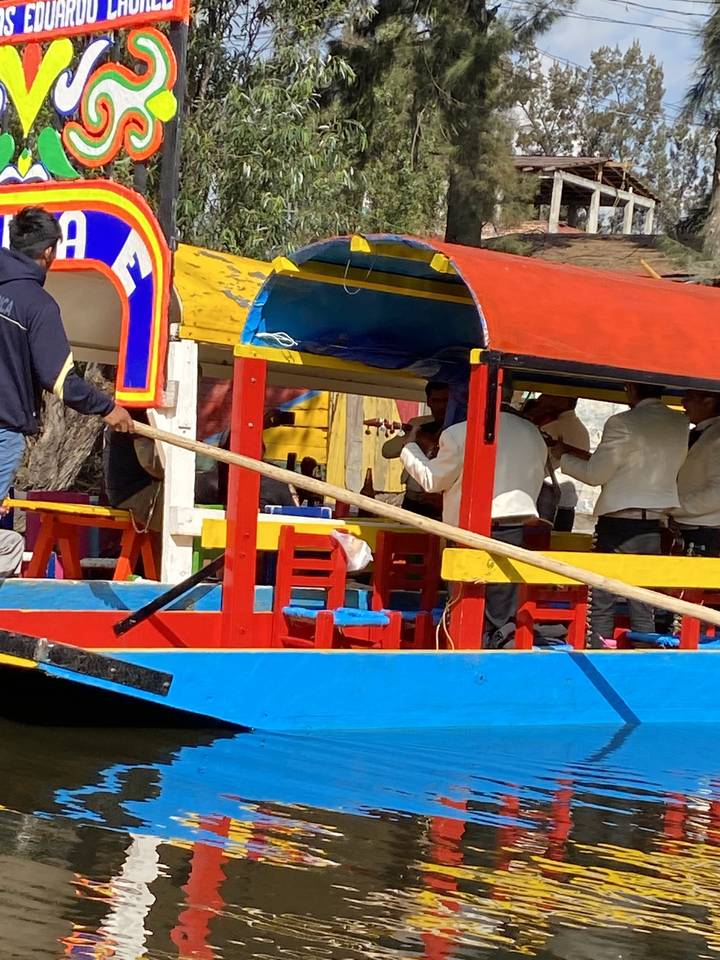 Bateaux colorés sur un canal avec des gens à bord.