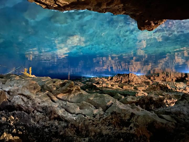 Beautiful cenote with blue water and rock formations.
